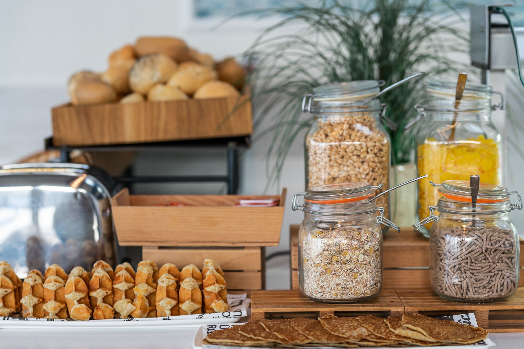 A breakfast buffet with various breads, cereals, and a fruit drink.