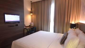 Une chambre d’hôtel avec un lit, un bureau, une télévision et des rideaux.