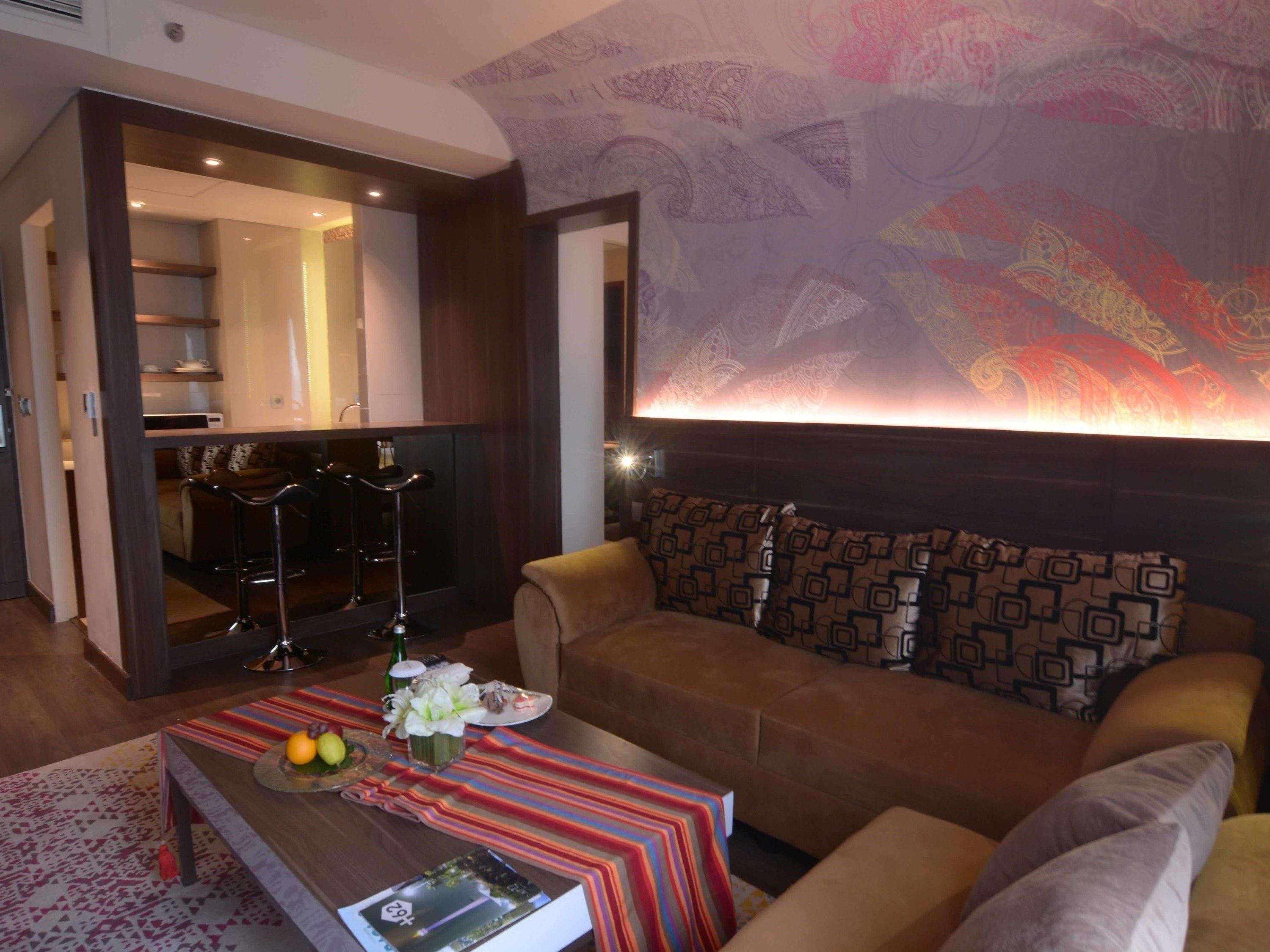 A modern living room with a sofa, a coffee table with a magazine, and a patterned wall.