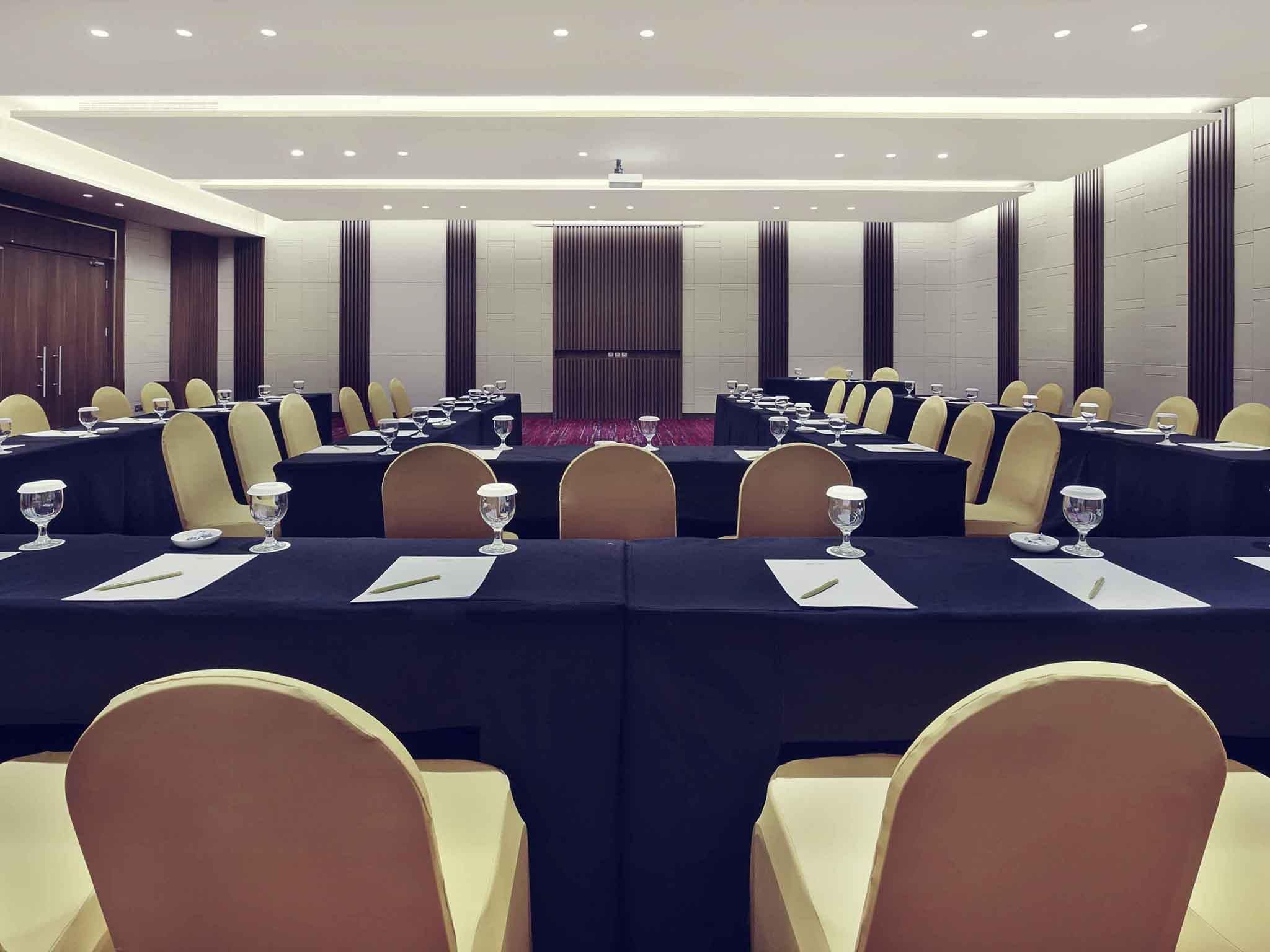 A conference room with tables set for meetings, equipped with chairs and glassware.