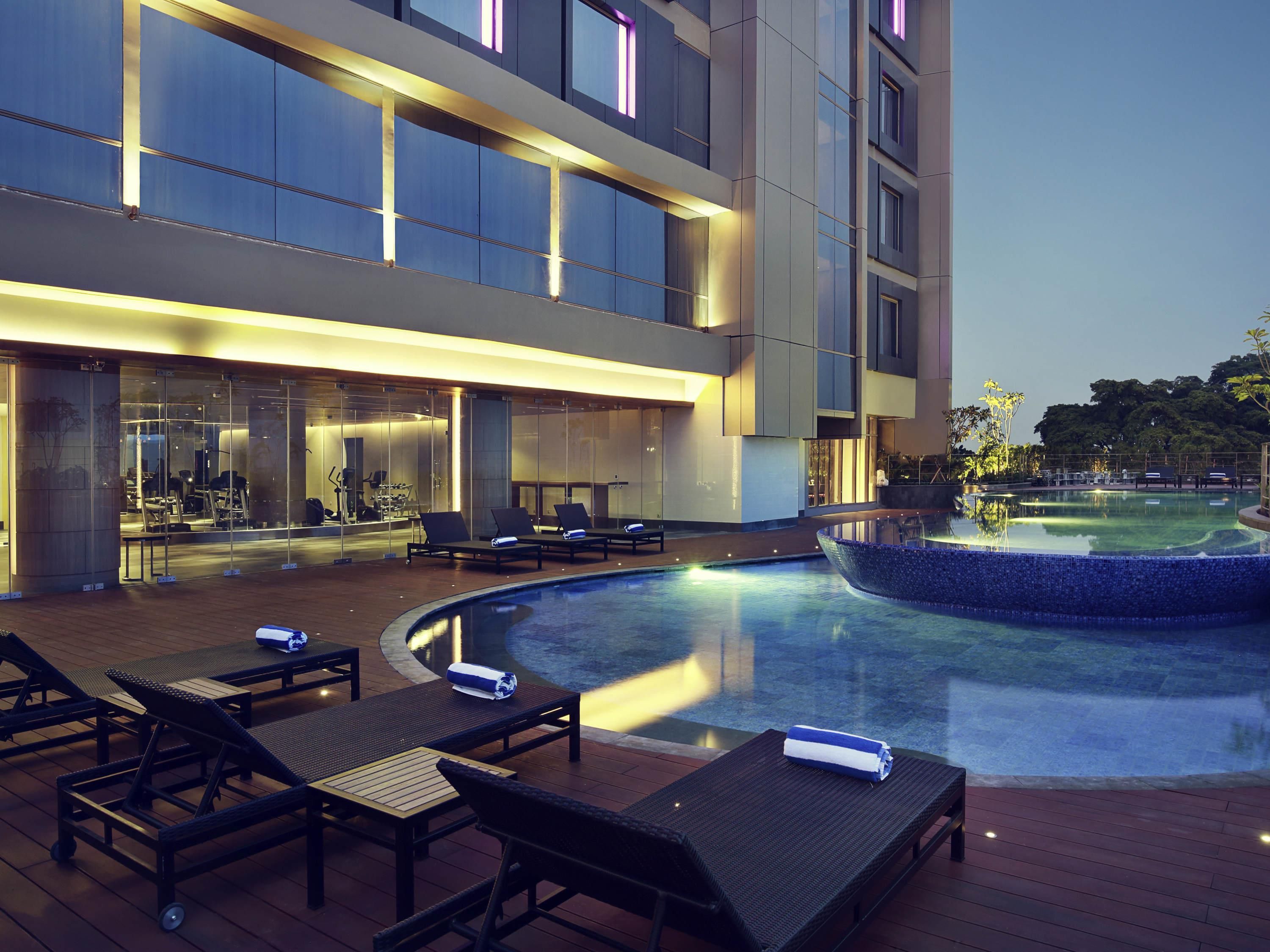 A modern hotel with a rooftop pool area featuring lounge chairs and a small fountain.