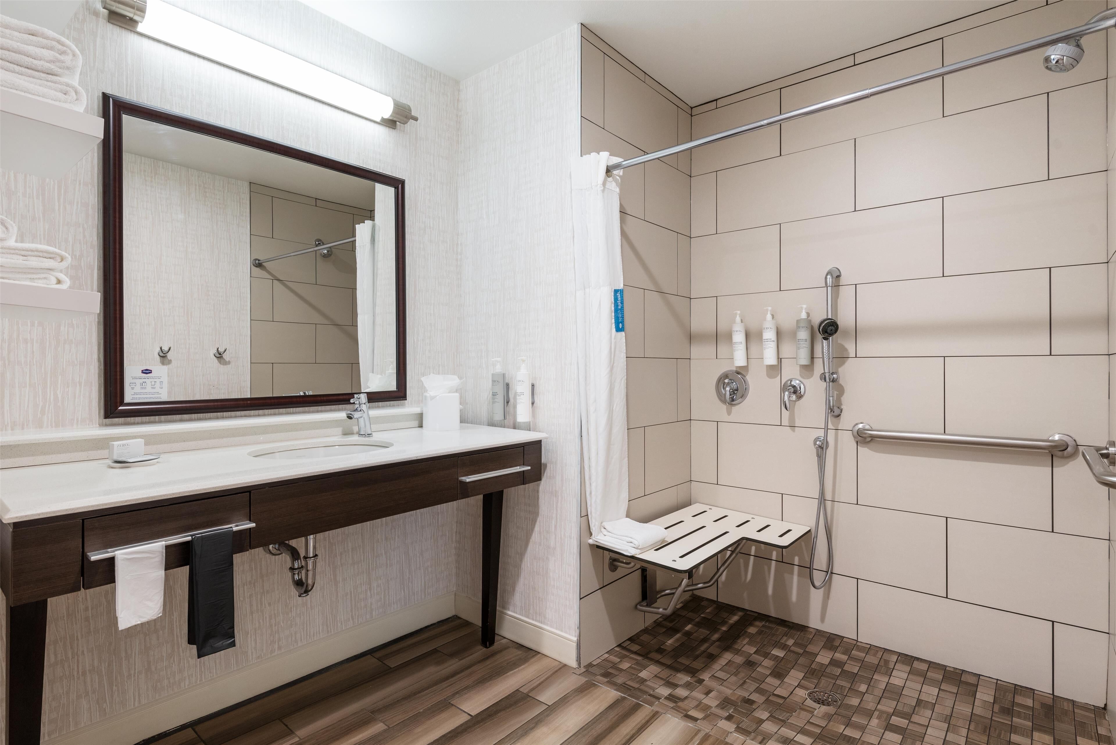Een moderne badkamer met een douche, een wastafel met spiegel en een handdoekhouder.