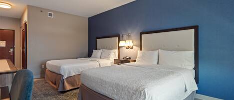 A hotel room with two beds, a desk, and a chair.