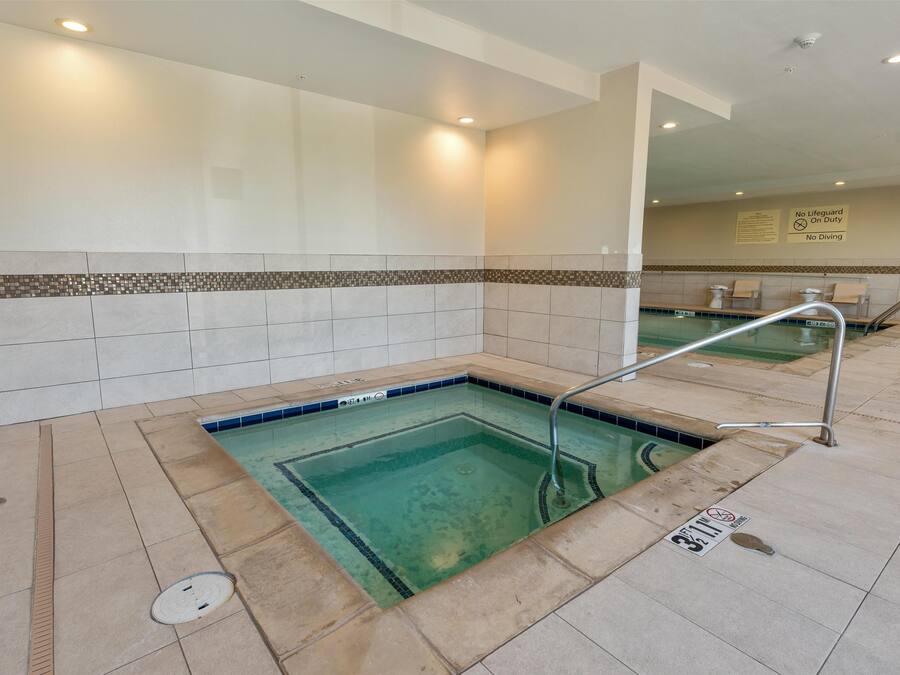 A pool area with a tiled floor, a metal handrail, and a sign indicating no diving.