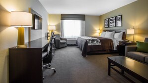 A hotel room with a bed, a desk, a chair, a sofa, and a TV mounted on the wall. - Sleep Inn & Suites Hannibal West (Hannibal)