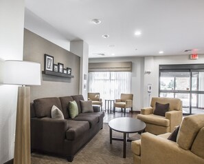 Relax in the stylish lobby with a sofa, armchairs, and a coffee table, surrounded by artwork and natural light.