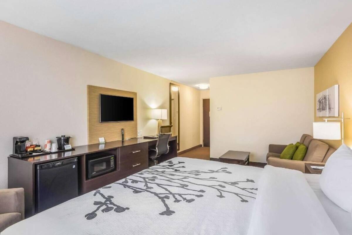 A hotel room with a bed, a desk with a computer, a TV, a microwave, and a coffee maker.
