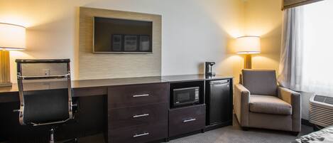 Habitación de hotel con escritorio, silla, microondas y aire acondicionado.