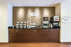 A breakfast bar with coffee machines, bowls, and cups.