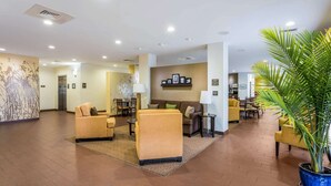 A spacious lobby with a reception desk, seating area, and a large potted plant.