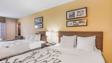 A hotel room with two beds, a nightstand, a lamp, and framed pictures on the wall.