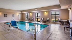 An indoor swimming pool with a lifeguard chair, poolside chairs, and a table with chairs. - Sleep Inn & Suites Hannibal West (Hannibal)