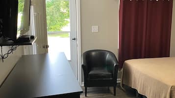 A room with a bed, a chair, a desk, and a television.