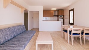 A compact living space with a sofa, a small dining table with chairs, a kitchenette, and a door leading to another room. - Vistamar I - MC Apartaments Ibiza (Ibiza Town)