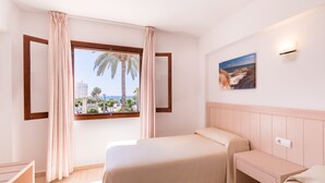 A hotel room with a bed, a bedside table, a window with curtains, a wall-mounted light, and a painting. - Vistamar I - MC Apartaments Ibiza (Ibiza Town)