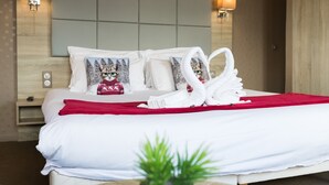 A hotel room with a bed, white bedding, a red throw blanket, two swan-shaped towels, and two wall-mounted lamps. - Hotel de la terrasse (Berck-sur-Mer)