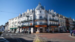 A historic hotel with a prominent dome and multiple balconies, located at a street corner with cars parked in front. - Hotel de la terrasse (Berck-sur-Mer)