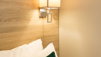 Een net opgemaakt bed met een groen kussen waarop staat 'What a Wonderful Life' en een bedlampje.