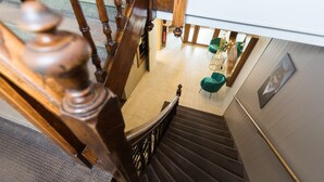 A wooden staircase leading to a room with a white ceiling and a green chair. - Hotel de la terrasse (Berck-sur-Mer)