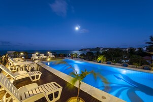 Una piscina al aire libre, sillones reclinables de piscina