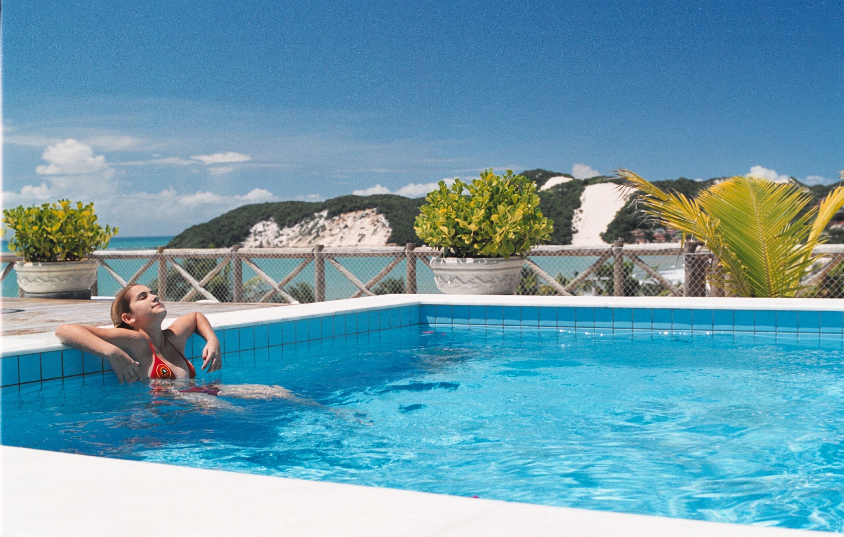 A pool with a clear view of the sea and hills in the background.