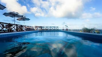 Una piscina al aire libre, sillones reclinables de piscina