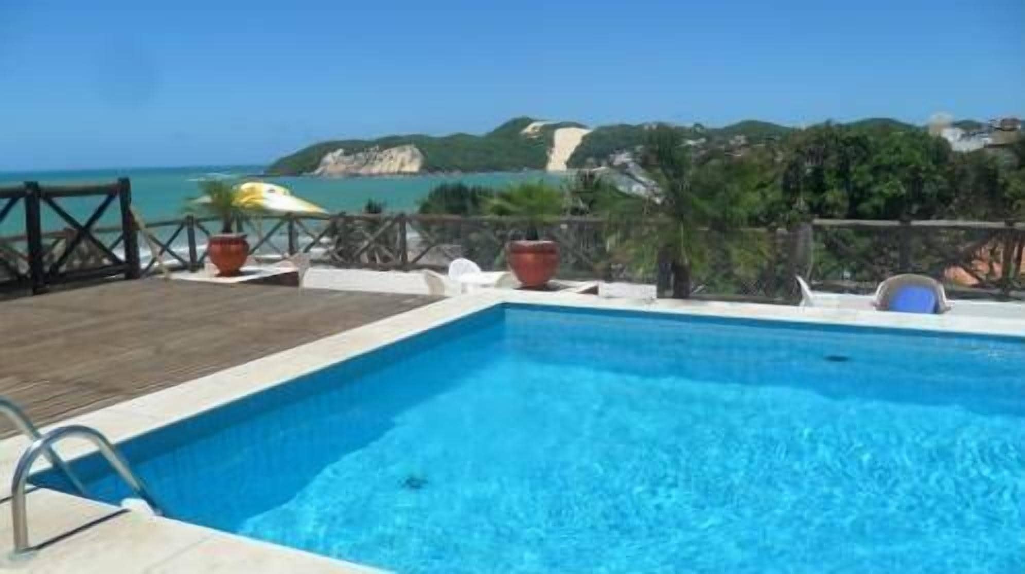 Una piscina con vista al mar y colinas al fondo.