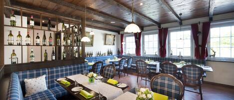 Un restaurante con techo de madera, mobiliario a cuadros azules y una vitrina de vinos.