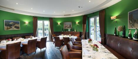 A restaurant with green walls, white tables, and brown leather booths.