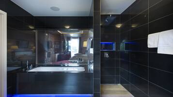 A modern bathroom with a large mirror, a bathtub, and a shower area.