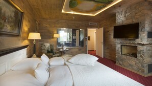 A hotel room with a large bed, a stone fireplace, a flat-screen TV, and a ceiling mural. - Landgut Ramshof (Willich)
