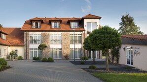 A two-story building with a tiled roof, stone facade, and multiple windows. - Landgut Ramshof (Willich)