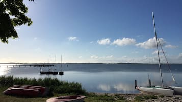 Um lago calmo com barcos atracados na margem e um cais que se projeta na água.
