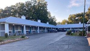 Un motel doté d’un parking central et de plusieurs chambres avec des auvents bleus.