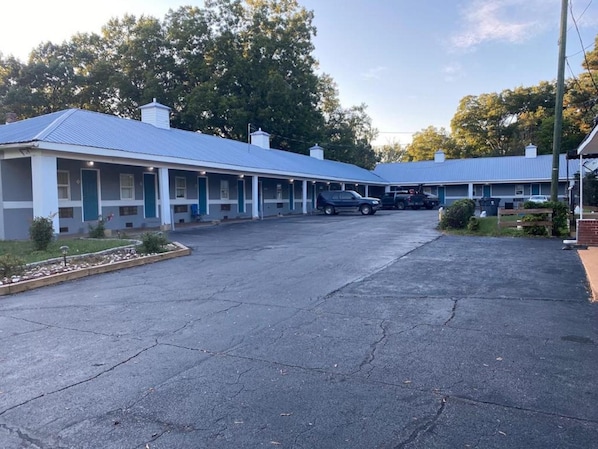 A motel with a central parking area and multiple rooms with blue awnings.