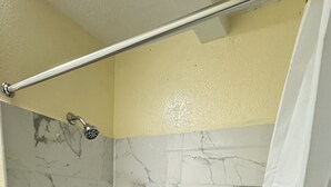 Une salle de bain avec une baignoire, des murs en marbre et un rideau de douche.