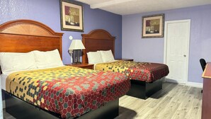 Une chambre avec deux lits, chacun doté d’une tête de lit en bois, d’une table de chevet avec une lampe et d’un tableau encadré au mur.