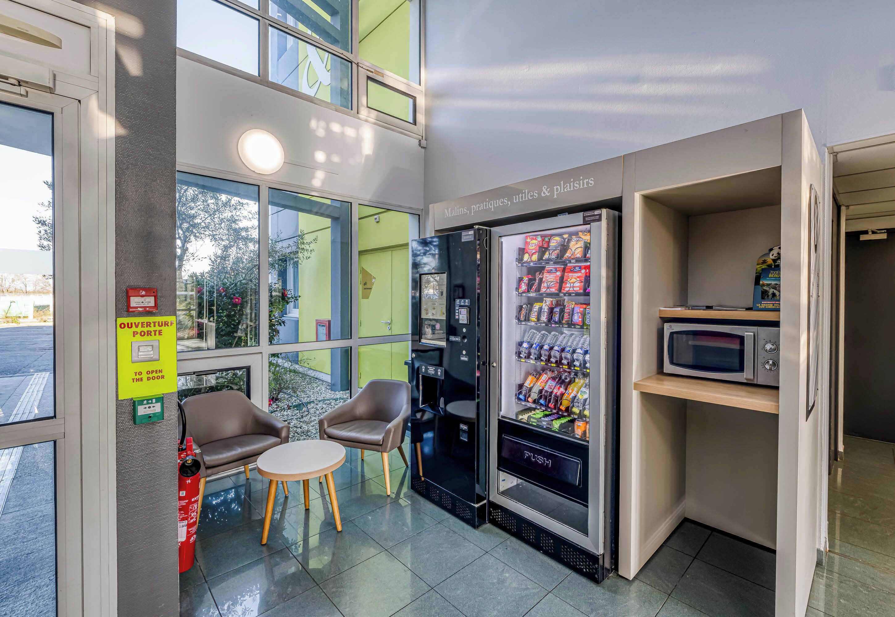 A modern interior with a vending machine, seating area, and a microwave.