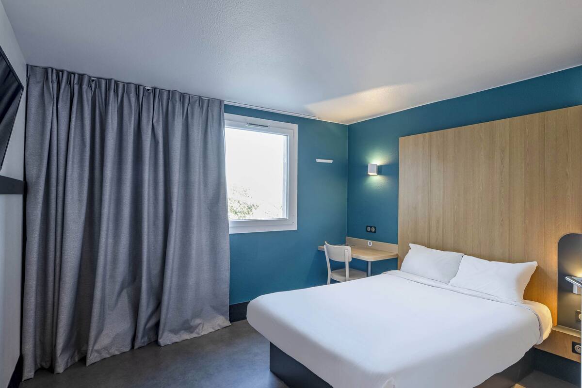 Une chambre d’hôtel avec un lit, un bureau et une chaise.