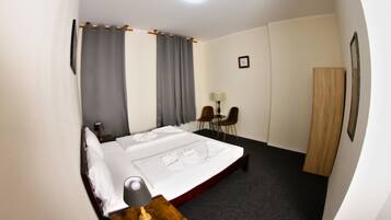 Une chambre d’hôtel avec un grand lit, un bureau avec une lampe, une chaise et une armoire.