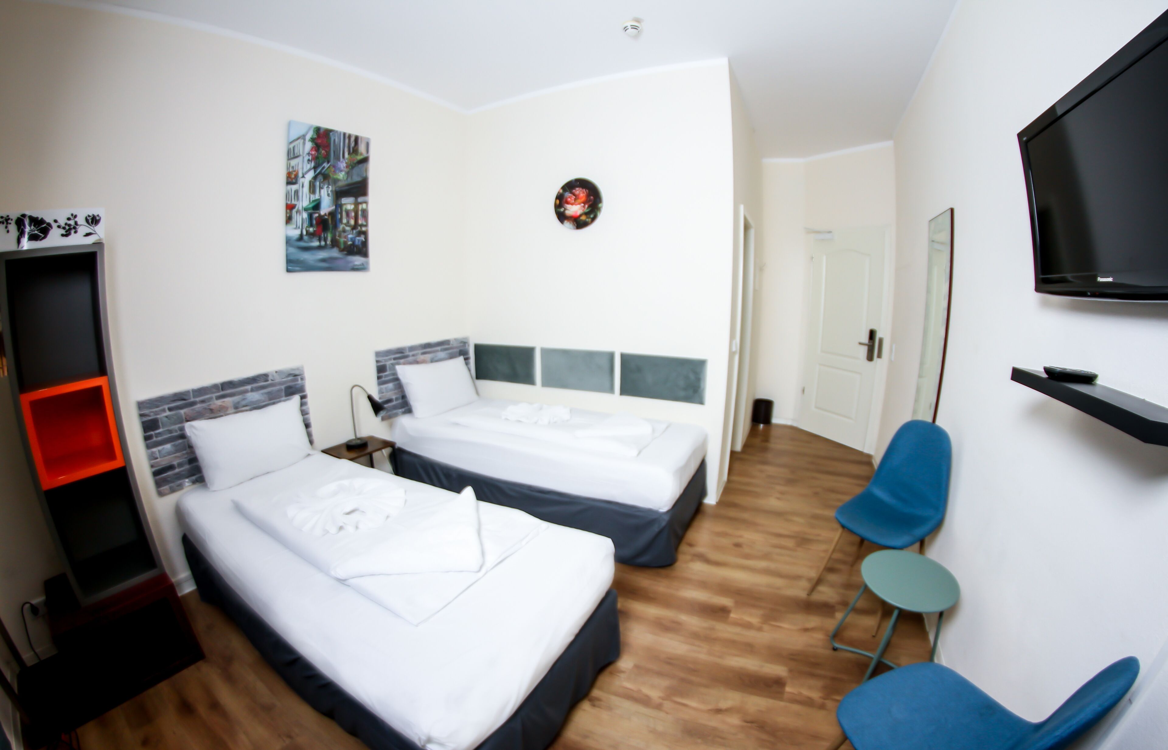 Ein Hotelzimmer mit zwei Betten, einem Fernseher, einem kleinen Tisch und einem Sessel.