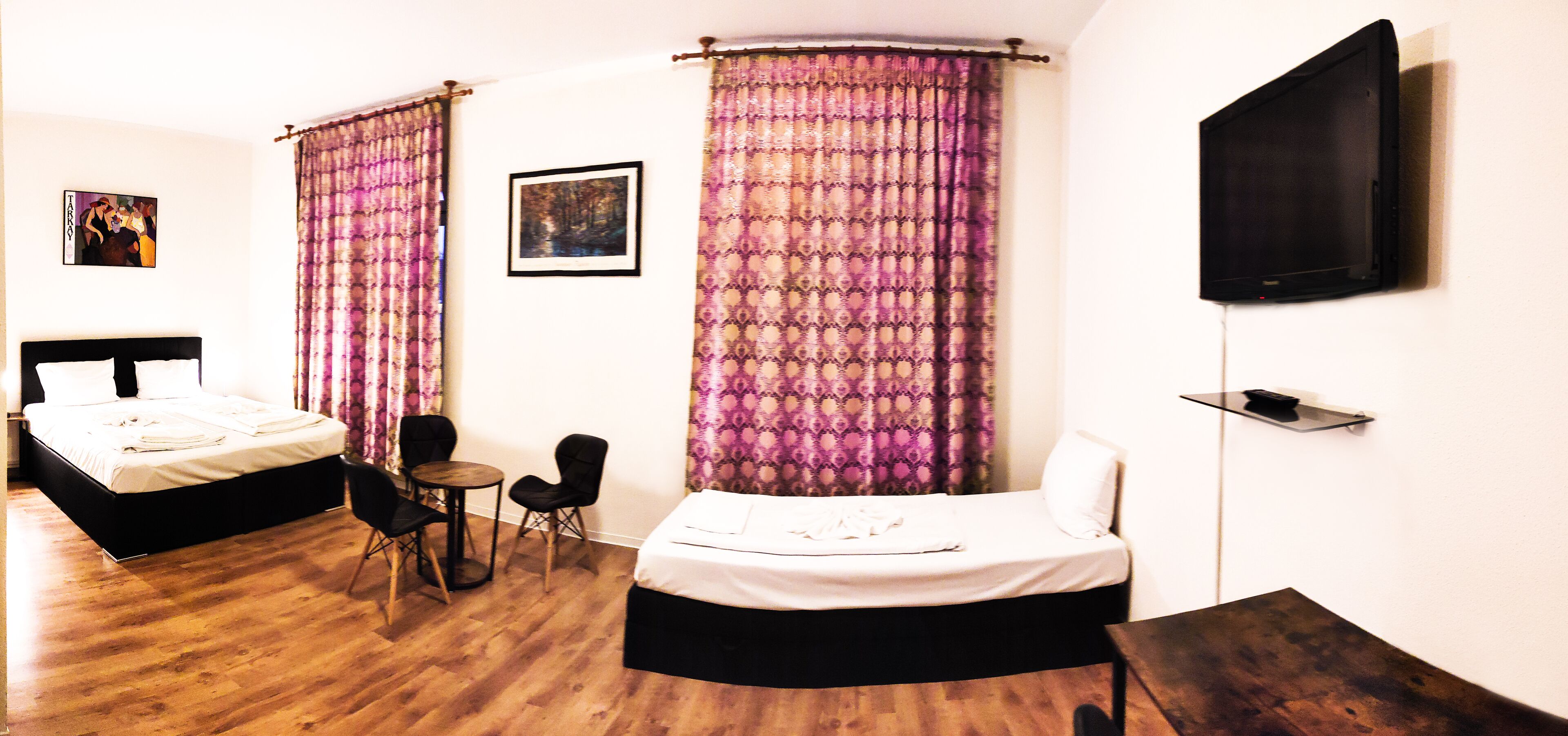 A hotel room with two beds, a TV, a small table, and chairs.