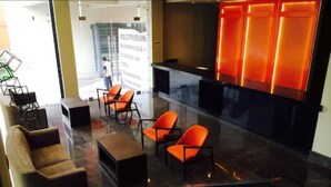 Eine moderne Lobby mit Empfangsschalter, Sitzgelegenheiten und einer Glastrennwand.