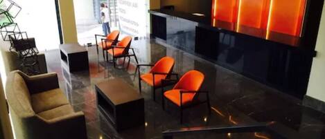 A modern lobby with a reception desk, seating area, and a glass partition.