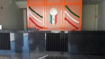 Zona de recepción con mostrador de mármol negro y paneles naranja con diseño de bandera.