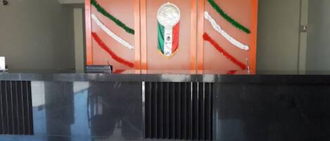 A reception area with a black marble counter and orange panels with a flag design.