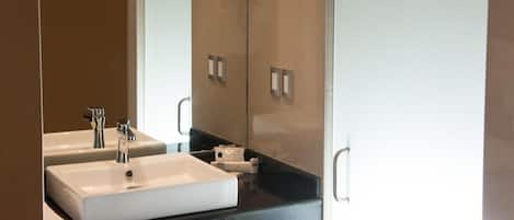Baño con dos lavamanos, un espejo y encimera negra.
