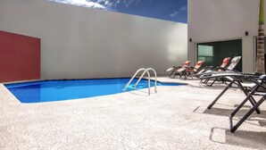 Ein Schwimmbecken mit Liegestühlen und einer Leiter.