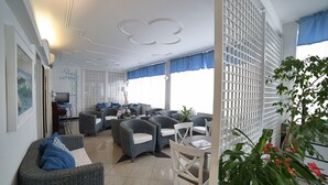 A modern living room with wicker furniture, a TV, and a balcony with a white lattice screen. - Hotel Villa Rosa (Sestri Levante)
