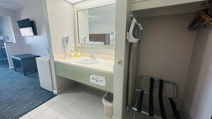 A hotel bathroom with a sink, mirror, hairdryer, and towel rack.